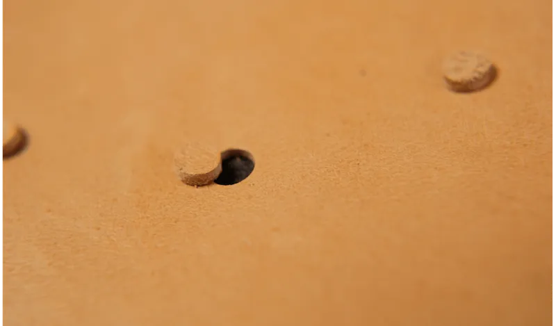 A round hole and a small punched disc in tan leather